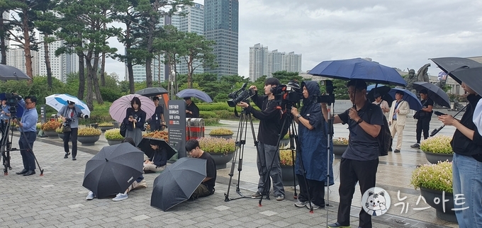 몰려든 취재진. 비가 내리는 중임에도 바닥에 앉아서 기사를 송고하고 있다. 뒤쪽으로 사복경찰들이 보인다.
