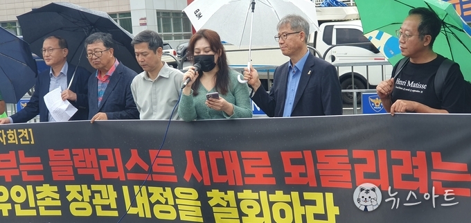 유인촌 장관 내정 철회를 요구하는 발정 중인 정윤희 디렉터, 그의 왼쪽 흰색 우산을 든 사람이 김신아 변호사이다. 